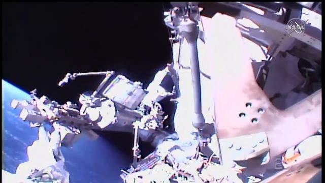 Spacewalkers work outside space station in helmet cam view